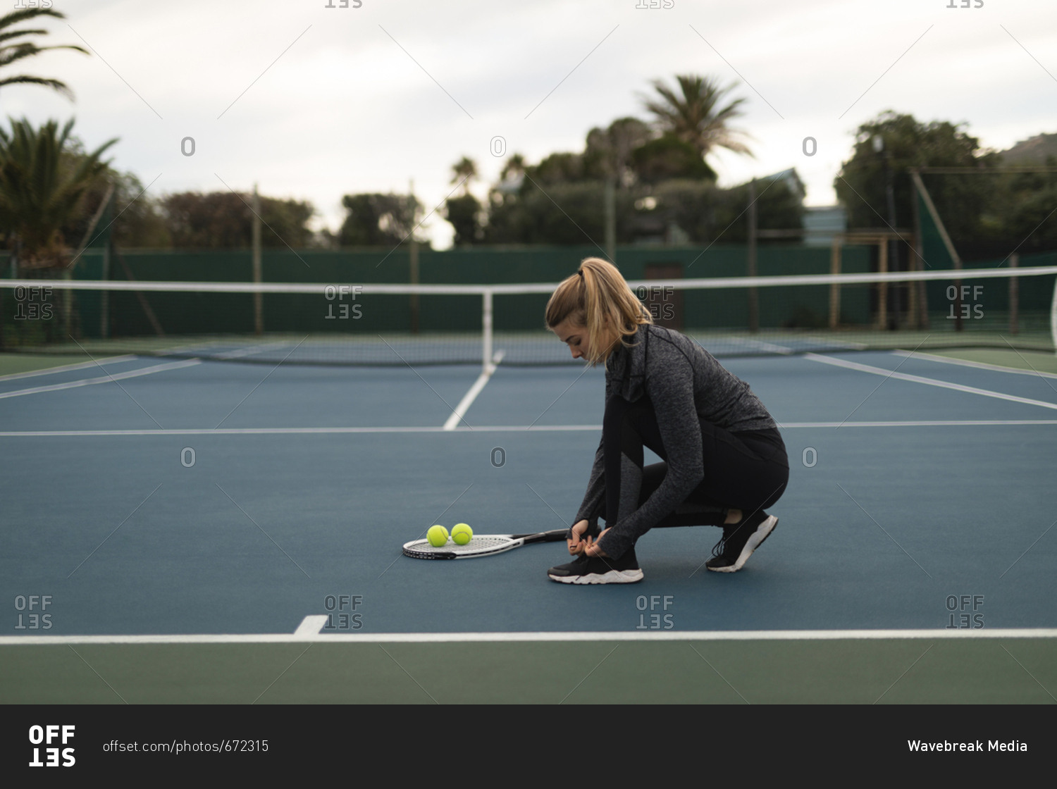Woman tying her shoelaces in tennis court