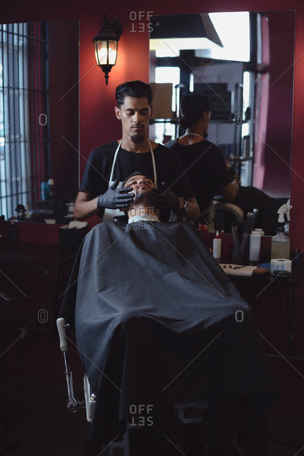 Barber applying cream on clients beard