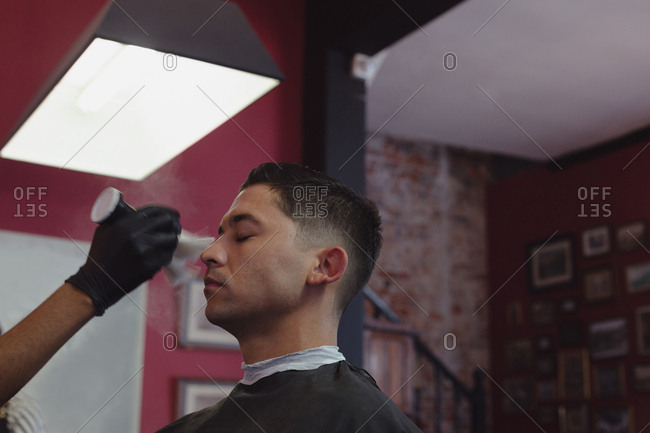 Barber cleaning customer face with brush