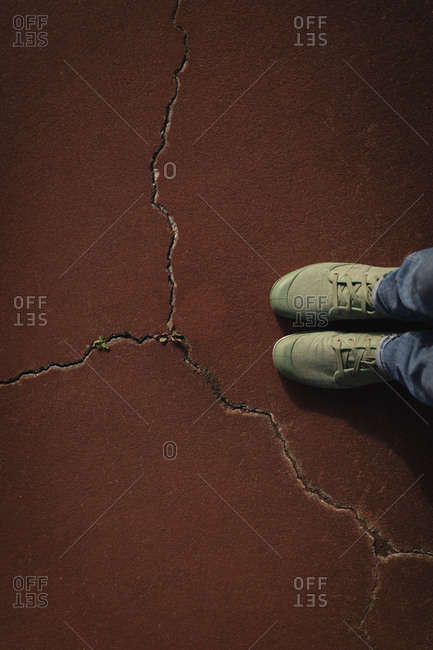 Woman standing in cracked tennis court