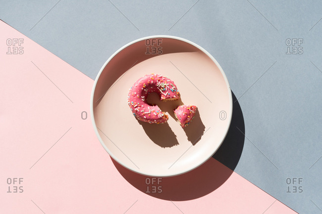 Top view of round plate on two colored backgrounds with glazed colorful doughnut.