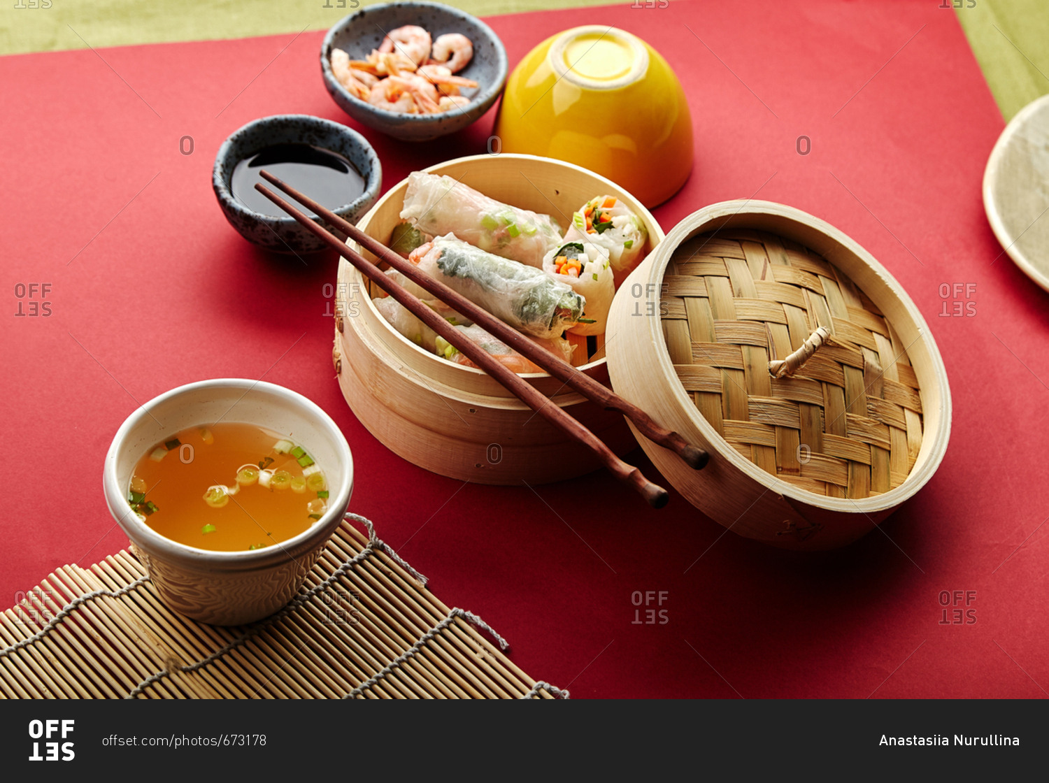 Spring rolls with shrimps and marinated vegetables in bamboo steamer on red background