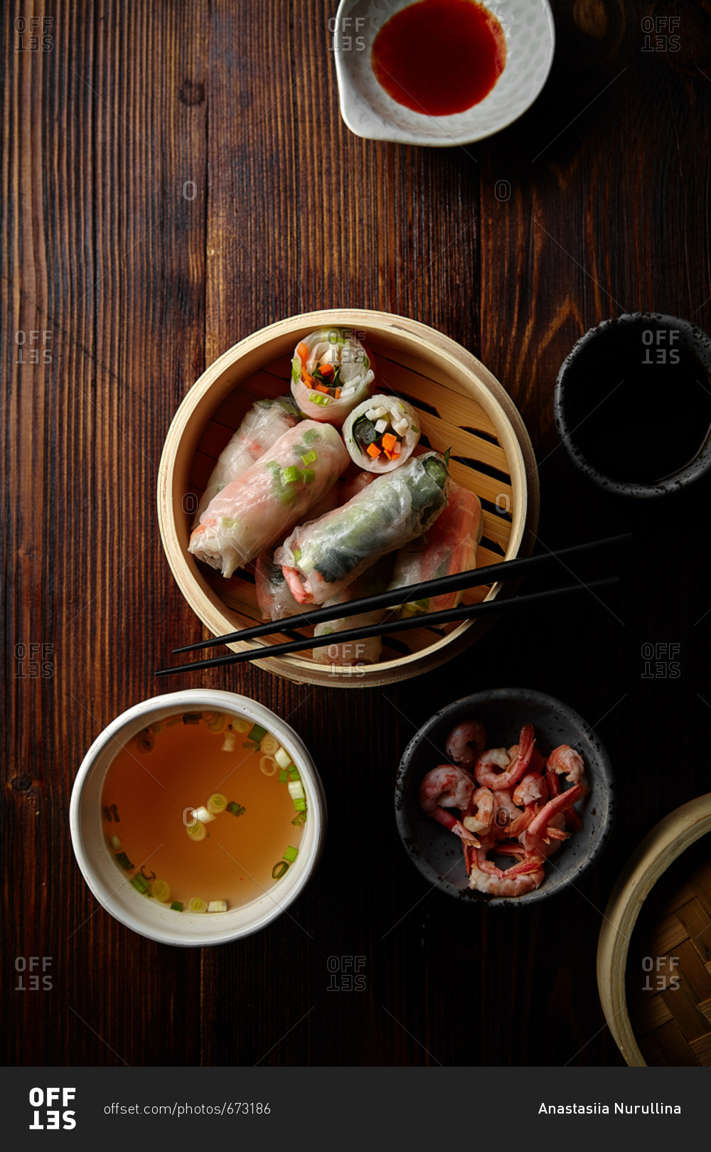 Spring rolls with shrimps and marinated vegetables in bamboo steamer on old wooden table