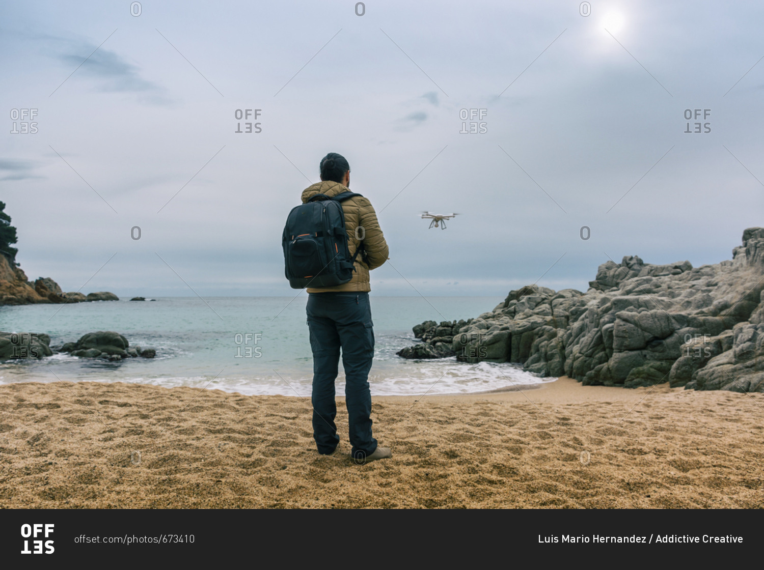 Man on a single beach testing its drone and recording videos from the air