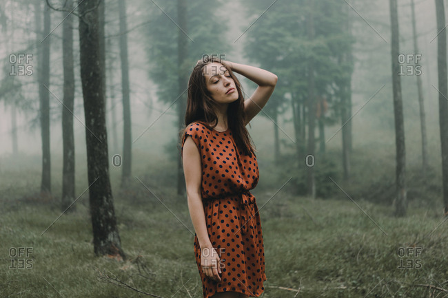 Model in dress standing in spooky woods