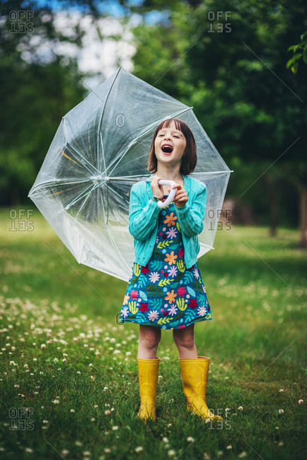 Young brunette girl posing with umbrella in vibrant spring children's fashion
