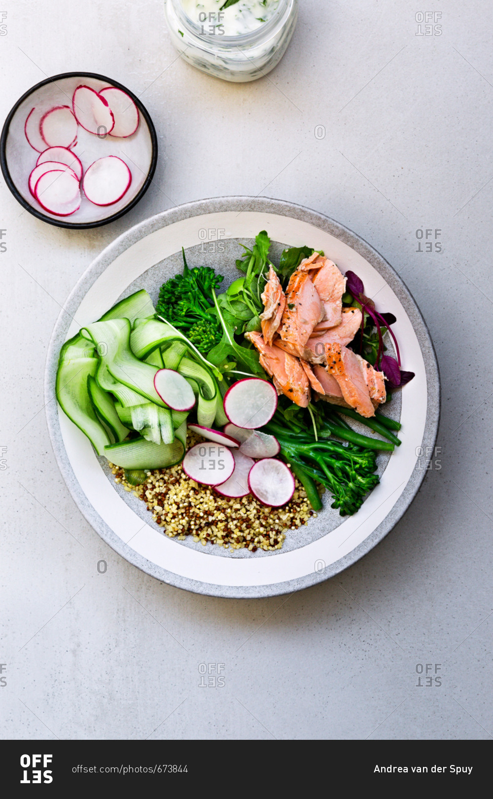 Ingredients for Salmon Buddha bowl, bowl of sliced radishes and jar of yoghurt on table