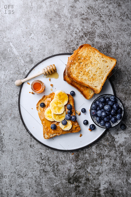 Toast with peanut butter, honey, sliced banana and blueberries