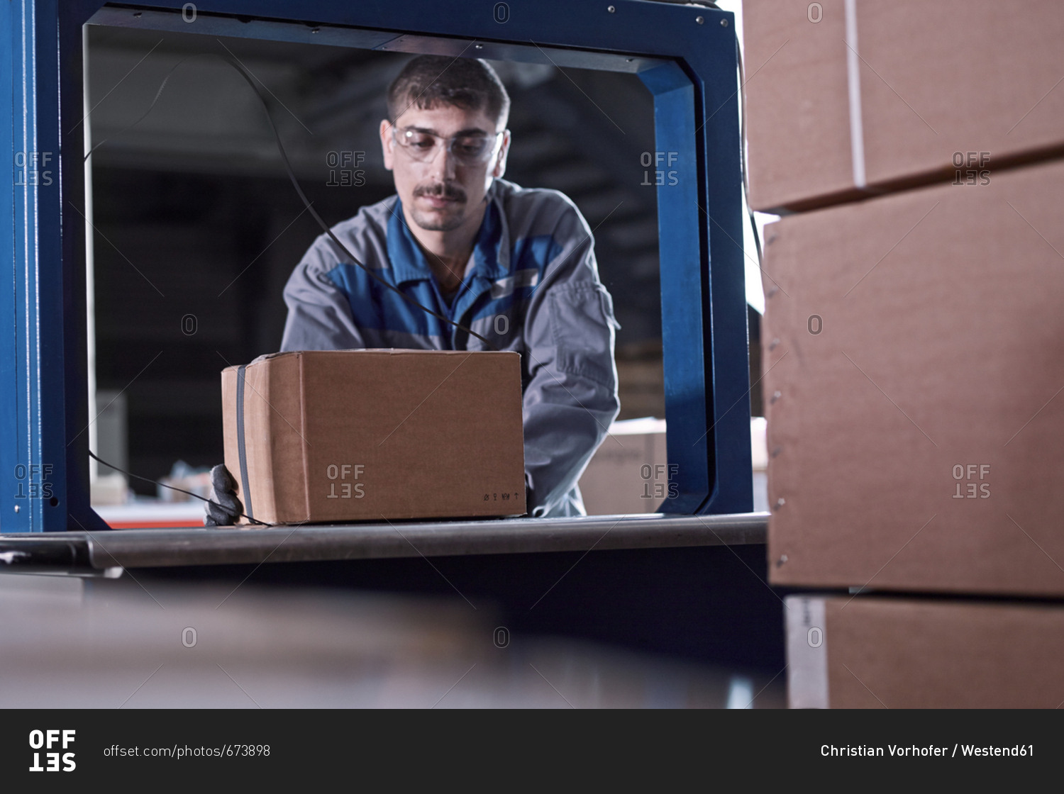 Worker watching machine closing packages