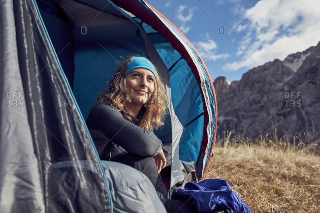 Smiling young woman sitting in tent in the mountains