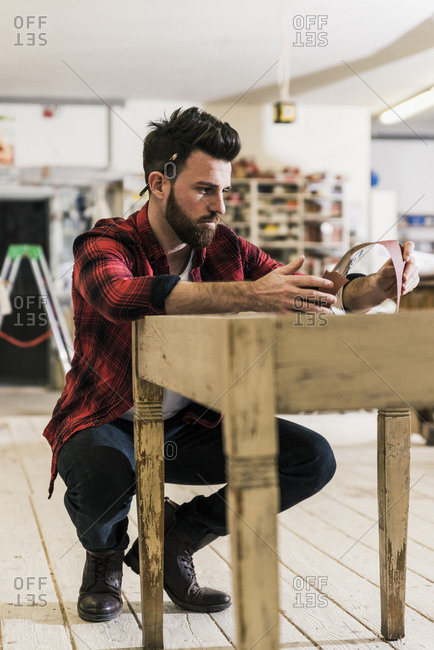 Man treating wood in workshop with sand paper