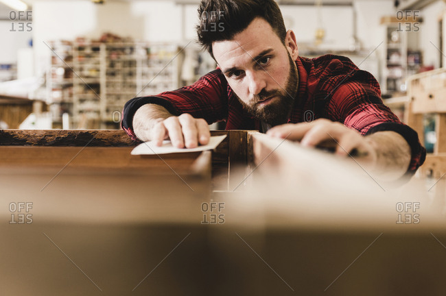 Man treating wood in workshop with sand paper