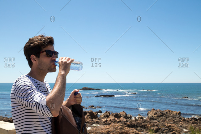 Man drinking water while exploring the oceanside