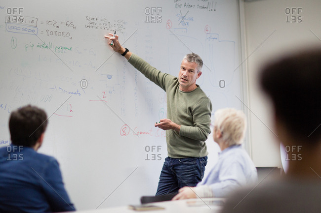 Teacher using white board in adult education course