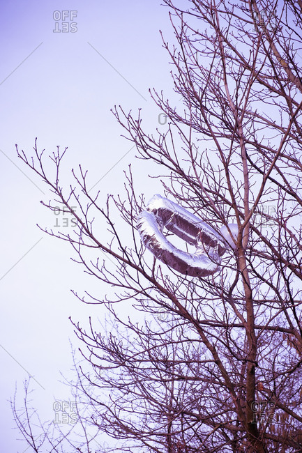 Stuck balloons in leafless tree against sky