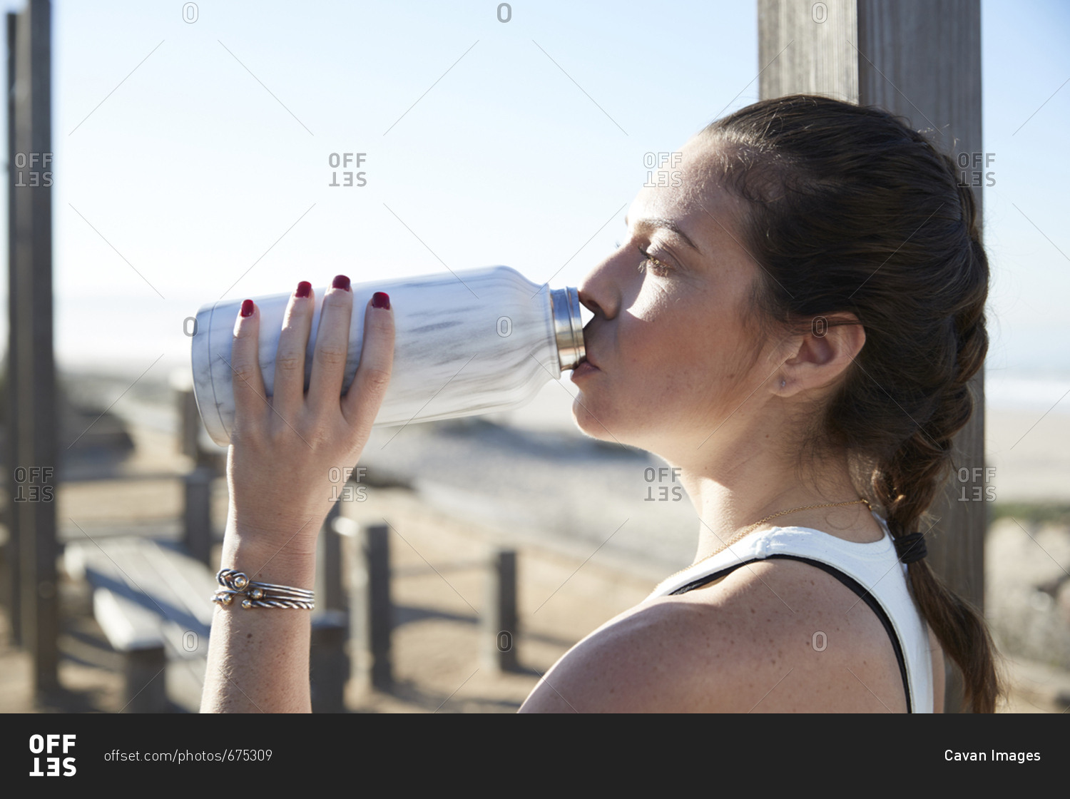Woman drinking water from bottle while exercising at beach