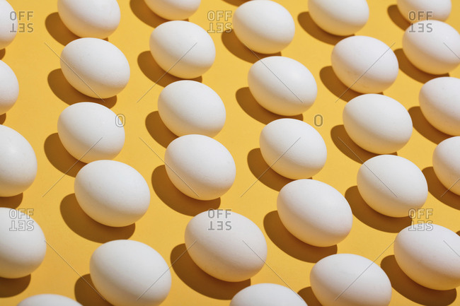High angle view of eggs arranged on yellow background
