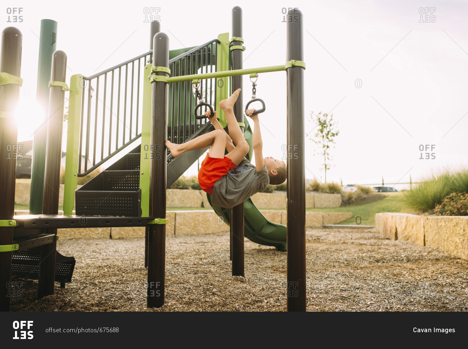 Playful boy hanging on outdoor play equipment while playing at playground