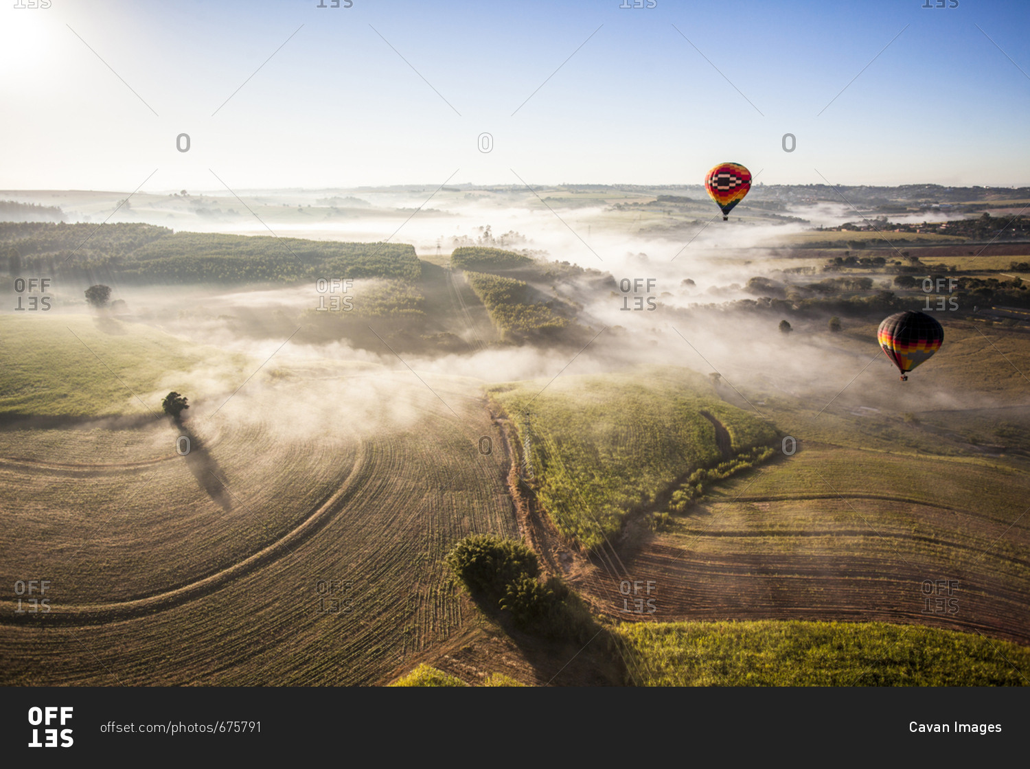 Aerial view of hot air balloons flying over landscape against sky during sunny day