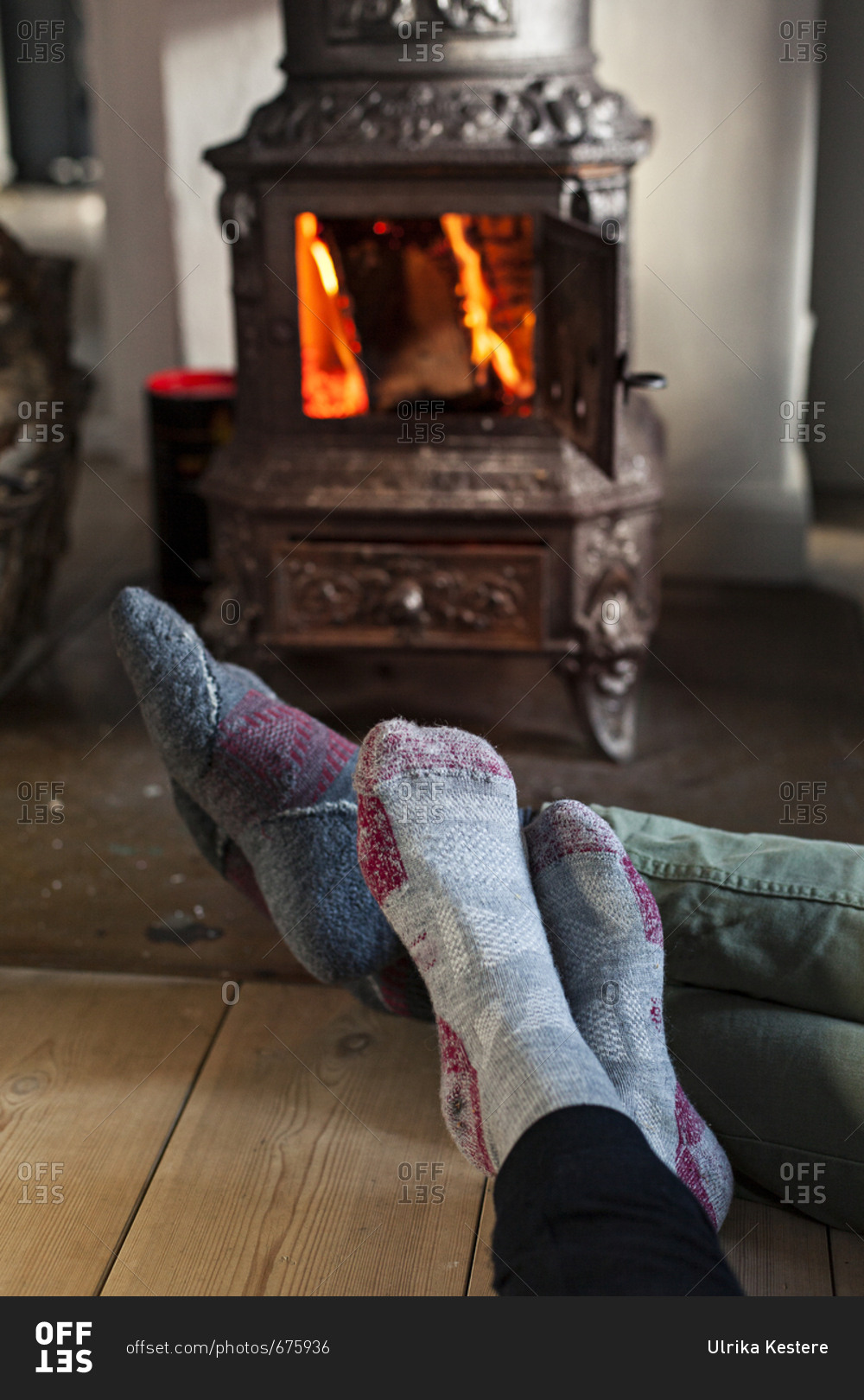 People wearing socks warming their feet near woodburning stove in