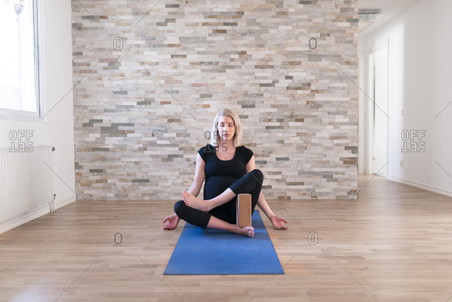 Pregnant woman practicing yoga using yoga block