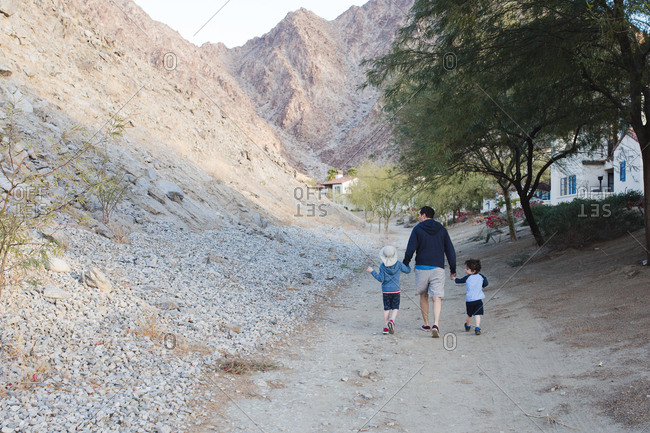 Dad takes his boys for a walk along path leading to arid hills