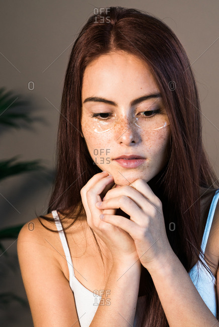 Woman with freckles wearing eye treatment
