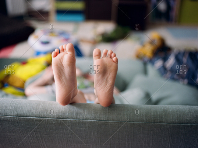 Little kid's feet sticking up over back of couch