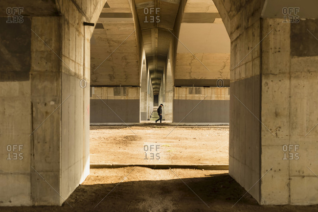Man walking between columns of bridge