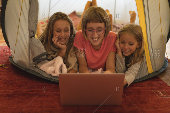 Happy siblings using laptop in a tent at home