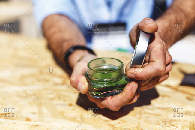 Man holding out a jar of green super food powder
