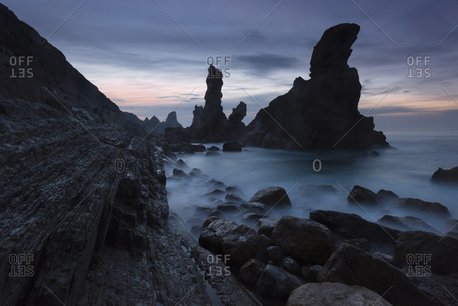 Dark blue evening mood on the coast near Santander with pinnacles and sea surf, Cantabria, Spain