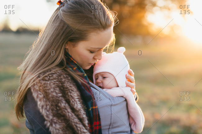 Mother and baby daughter outdoors, mother carrying baby in baby sling