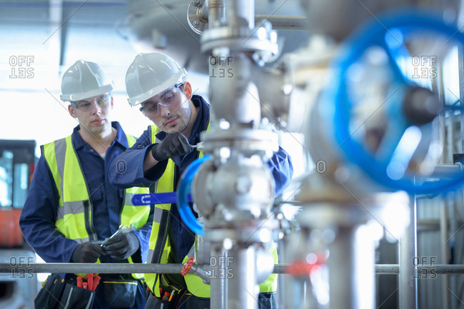 Apprentice engineers working on pipeline in industrial product facility