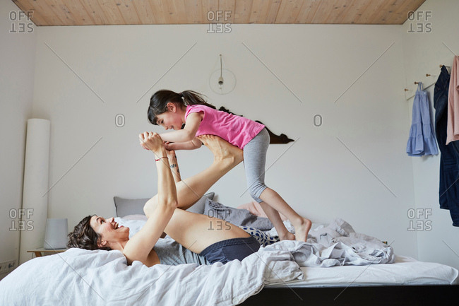 Mother and daughter playing in bedroom, mother balancing daughter on feet