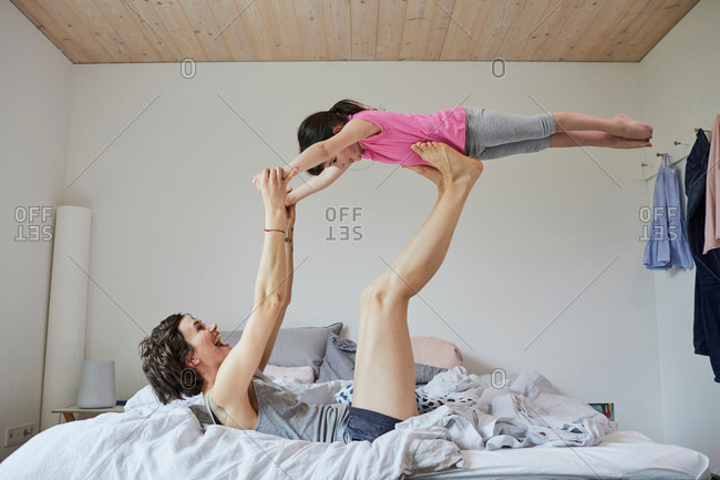 Mother and daughter playing in bedroom, mother balancing daughter on feet