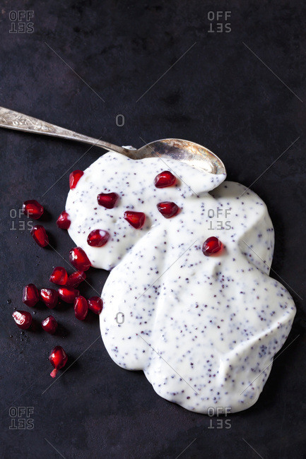 Natural yoghurt with poppy seed and pomegranate seed on dark ground