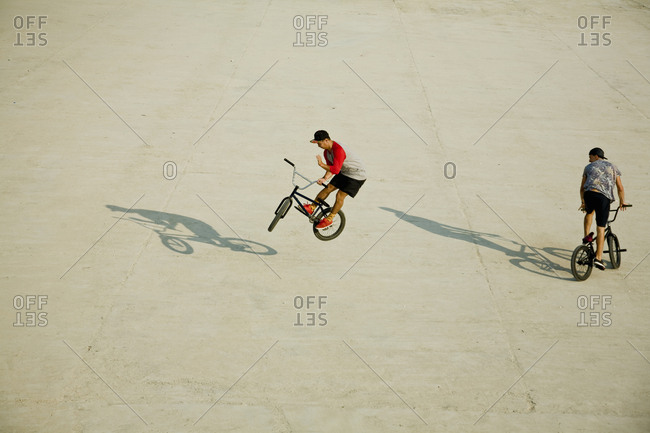 Young men riding BMX bikes on flat land, Budapest, Hungary