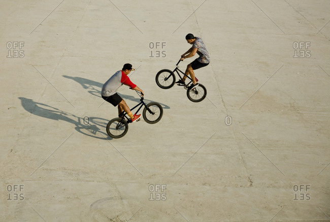 Young men riding BMX bikes on flat land, Budapest, Hungary