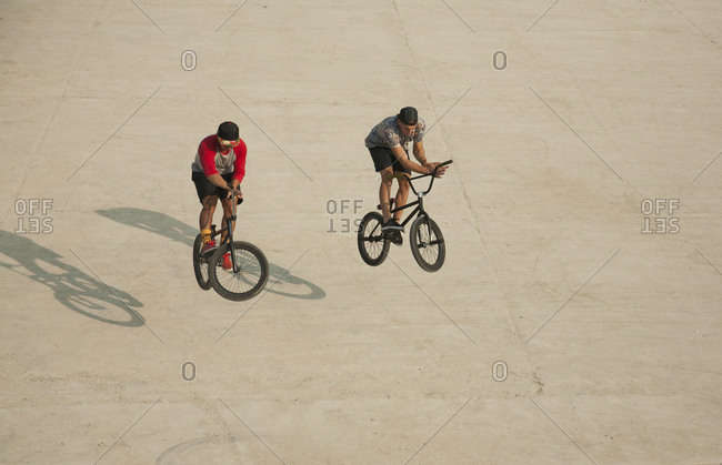 Young men riding BMX bikes on flat land, Budapest, Hungary