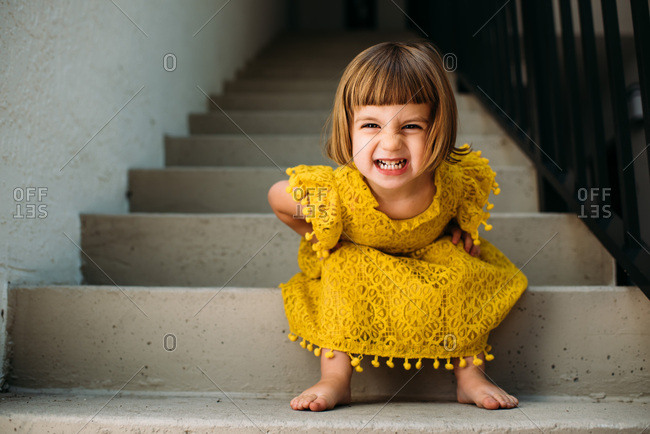 Little Girl Sitting On Steps Making A Funny Face Stock Photo Offset