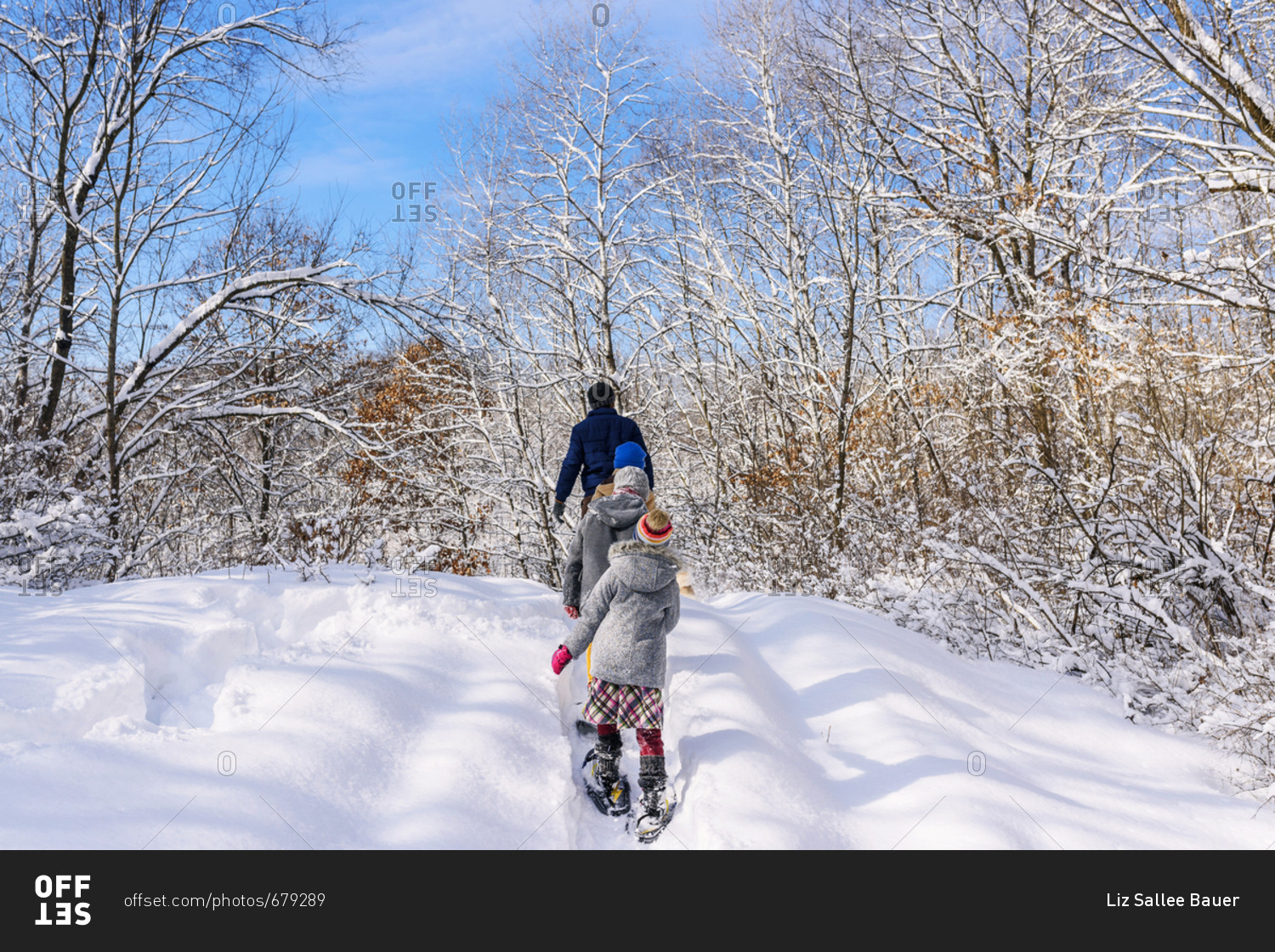 Family with young kids outside in the winter with snow shoes walking uphill