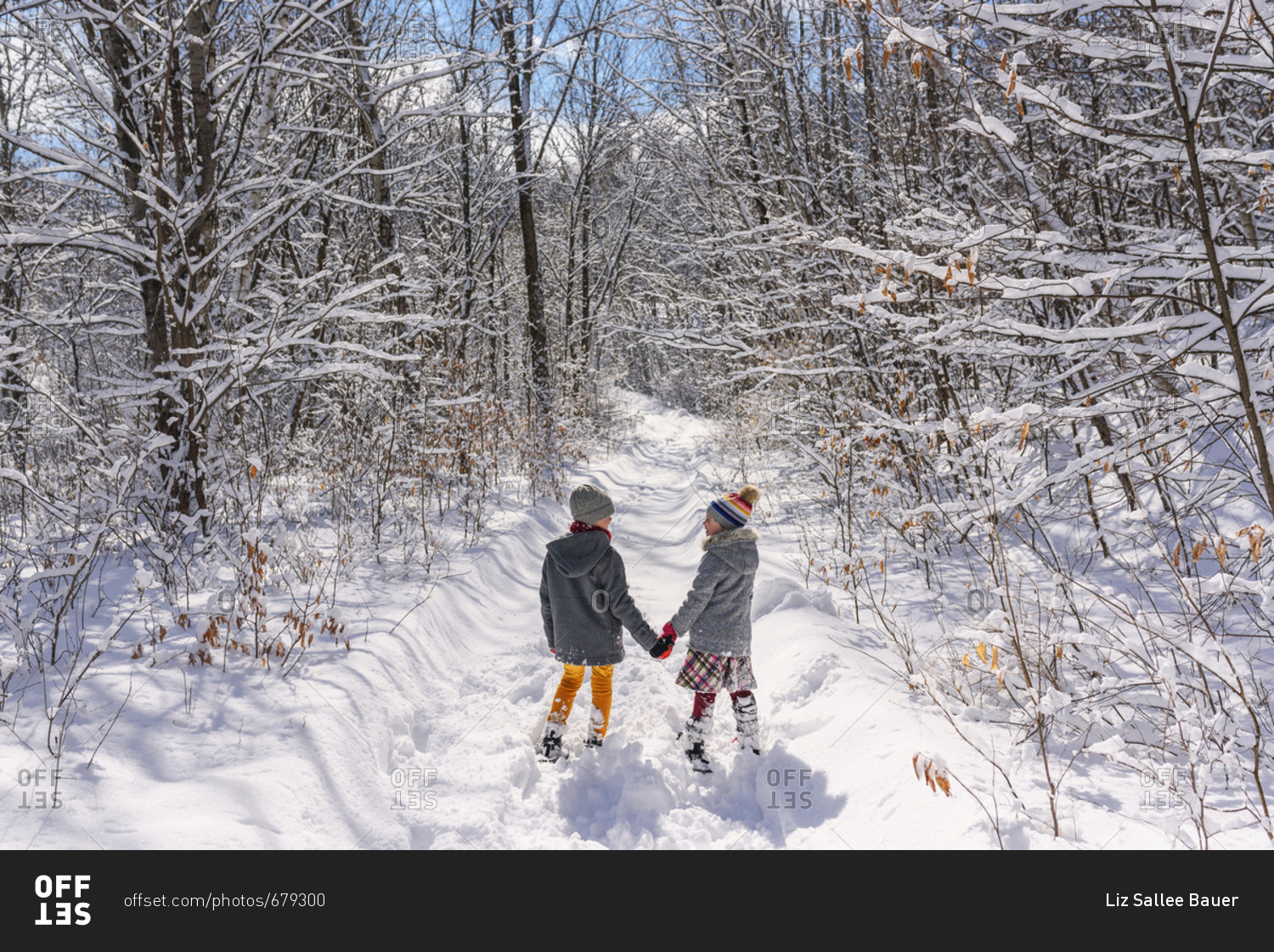 Two little kids holding hands outside in the winter with snow shoes