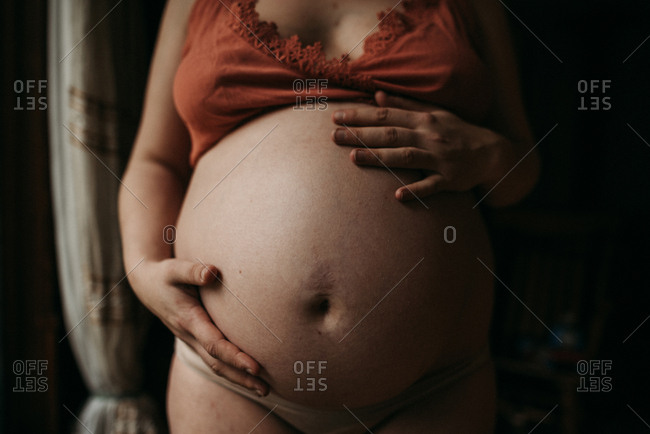 Woman's hands resting on stomach in maternity portrait