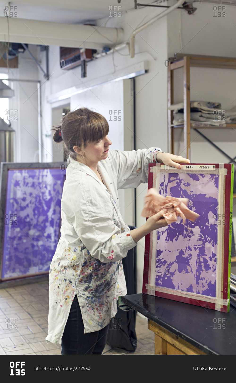 Textile designer wiping down stencil for screen print in studio