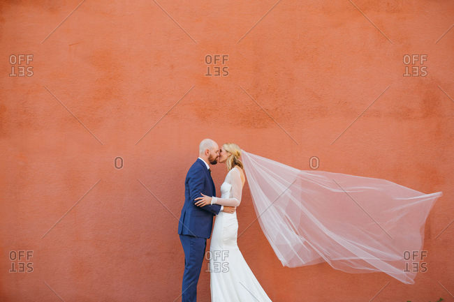 Bride and groom smiling after kiss with wind blowing veil