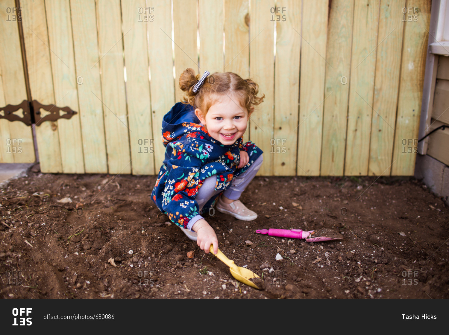 Little girl digging in dirt with small shovel stock photo OFFSET
