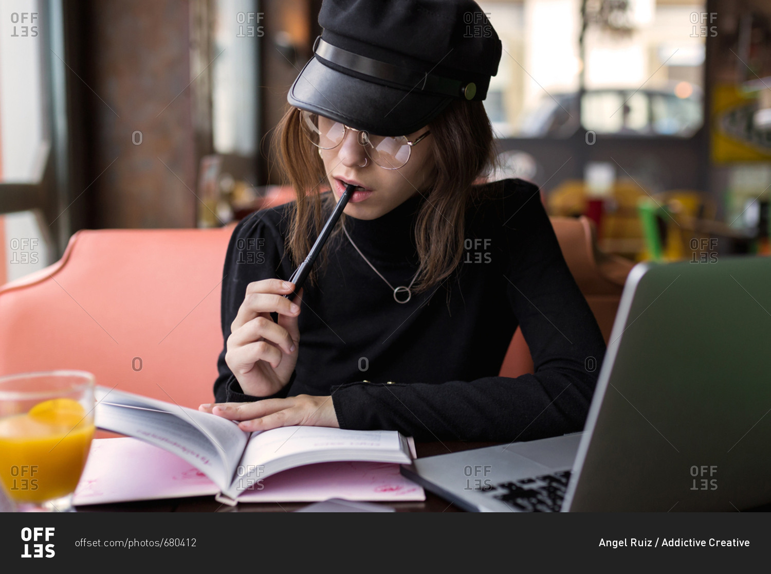 Woman with pen in mouth at laptop