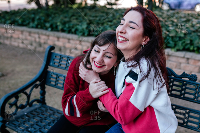 girlfriends sitting on the bench in a park