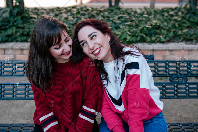 girlfriends sitting on the bench in a park